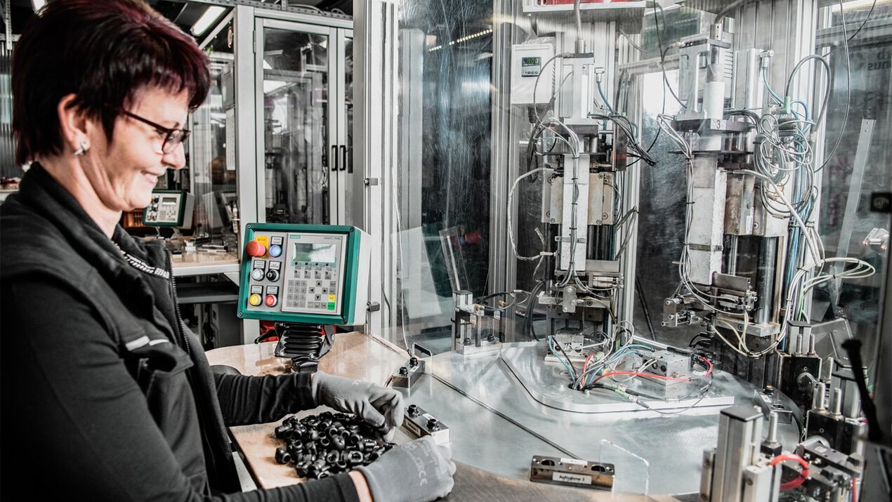 Mitarbeiterin arbeitet konzentriert an einer Kerb Konus Maschine bei der Buchsenmontage