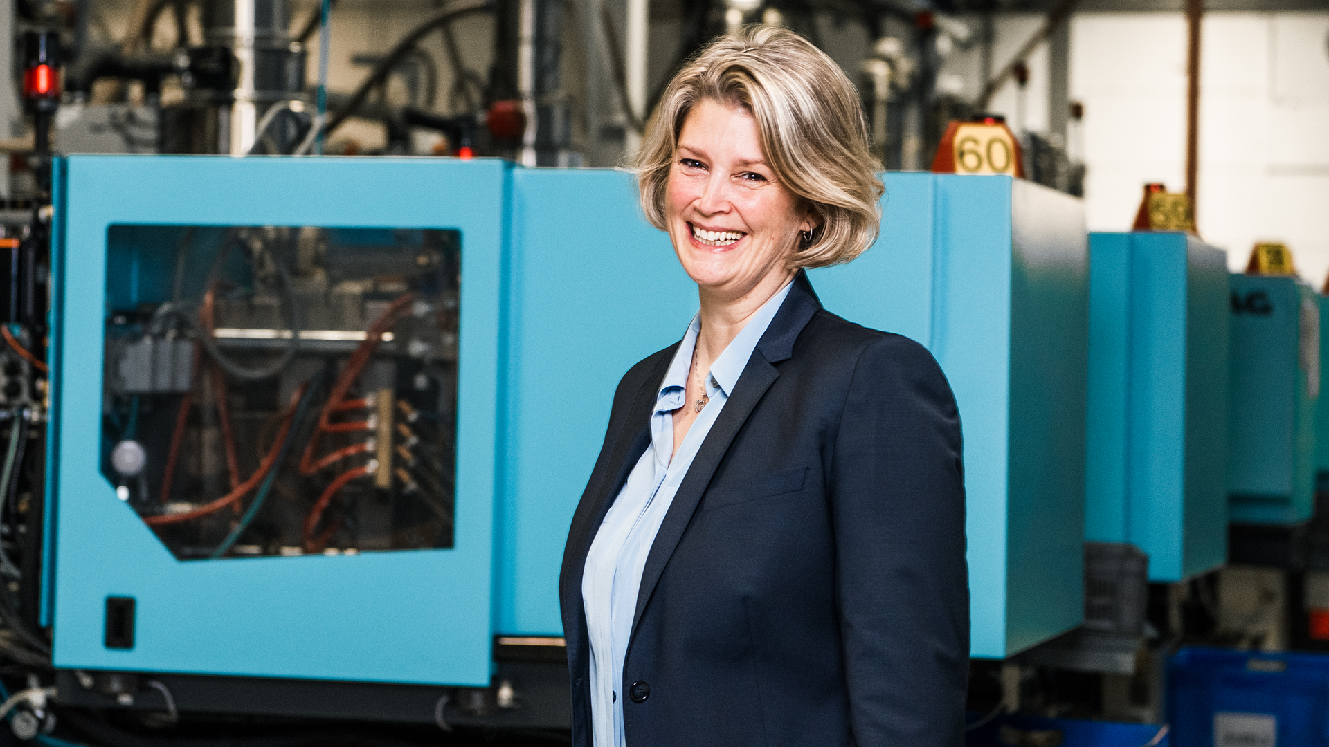 Aline Henke, Geschäftsführerin der hankensbütteler kunststoffverarbeitung, lachend in der Fertigungshalle