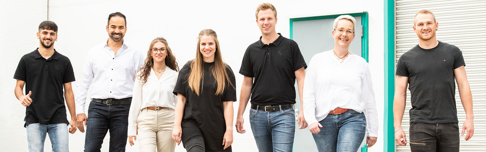 Mitarbeitende der hankensbuetteler kunststoffverarbeitung laufen lachend auf die Kamera zu und zeigen Teamgeist und Freude an der Arbeit